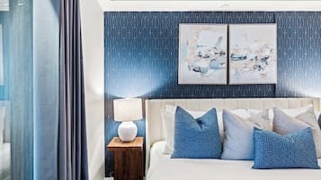 A bedroom with a bed, a nightstand, a lamp, and abstract wall art.