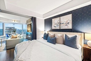 Quarto de hotel moderno com uma cama grande, vista para a cidade e varanda.