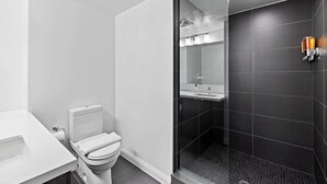 Une salle de bain moderne équipée de toilettes, d’un lavabo et d’une zone douche.