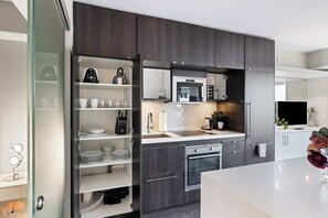 Eine moderne Küche mit dunklen Holzschränken, einem Edelstahlkühlschrank und einem Einbauofen.