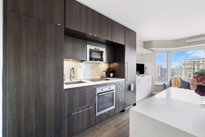 A modern kitchen with dark wood cabinets, stainless steel appliances, and a white countertop. - Boutique Yorkville Residence Walk Luxury Row | Parking Available (Toronto)