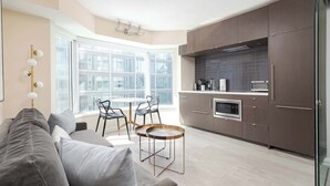 A modern kitchen with dark wood cabinets, a built-in oven, and a large window. - Designer 4 Seasons Luxury Bldg of Yorkville! (Toronto)