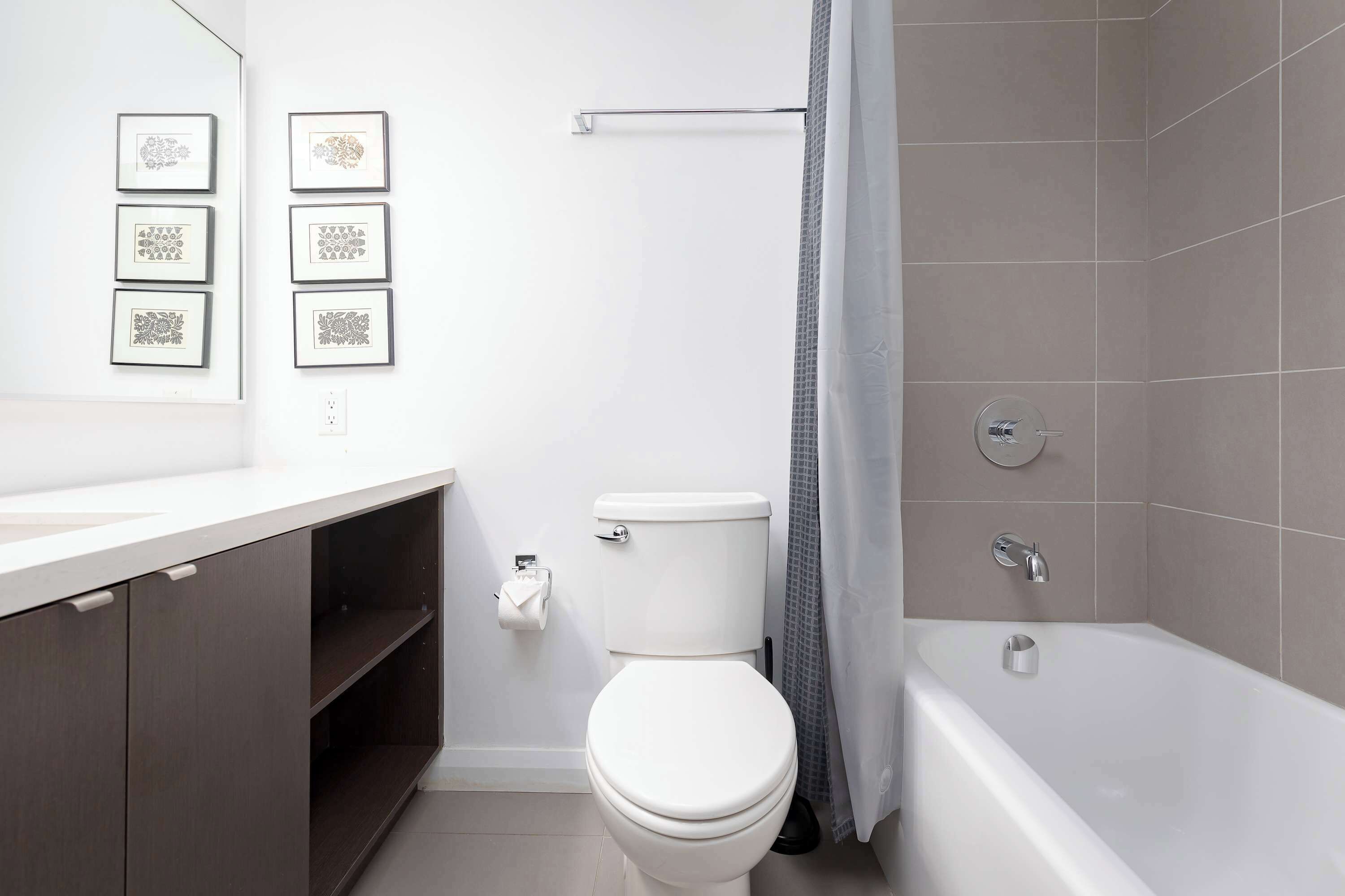 Un baño moderno con inodoro, bañera y perchero para toallas.