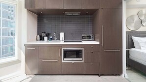 A compact kitchen with a built-in oven, microwave, and a coffee maker on the countertop. - Designer 4 Seasons Luxury Bldg of Yorkville! (Toronto)