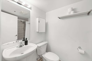 A modern bathroom with a white sink, mirror, toilet, and shower. - Modern Studio by Massey Hall | Heart of Toronto | Parking Available (Toronto)