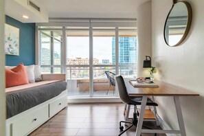 A modern bedroom with a large window, a desk, and a bed with storage drawers. - Spacious 3BR Downtown Condo with Free Parking | Parking Available (Toronto)