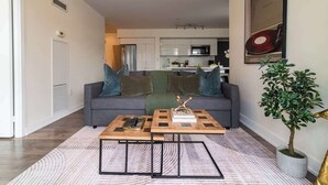 En moderne stue med en grå sofa, et sofabord og en potteplante.