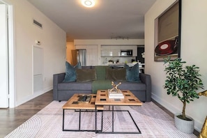 Ein modernes Wohnzimmer mit einem grauen Sofa, einem Couchtisch und einer Topfpflanze.
