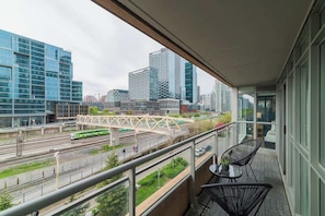 Ein Balkon mit Blick auf eine Stadtlandschaft, darunter moderne Gebäude und eine Bahnstrecke.