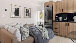 Un dormitorio moderno con una cama, un sofá y una kitchenette.