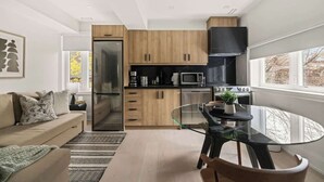 Una cocina moderna con armarios de madera, una mesa de comedor de vidrio y un horno empotrado.