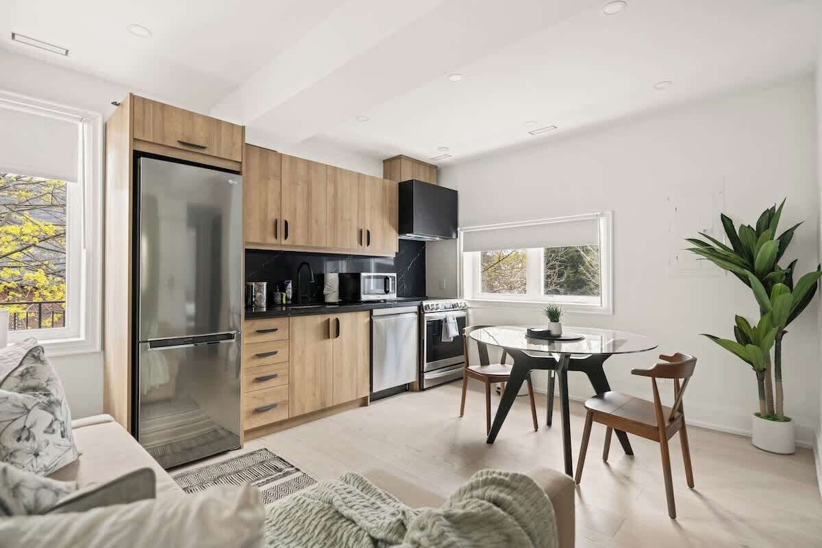 A modern kitchen with a built-in refrigerator, microwave, and oven. There is a dining area with a round table and chairs.