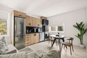 A modern kitchen with a built-in refrigerator, microwave, and oven. There is a dining area with a round table and chairs.