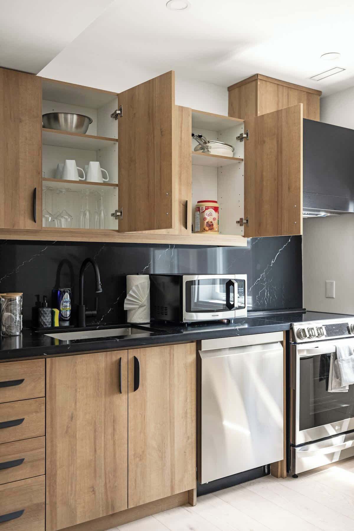 A modern kitchen with wooden cabinets, a stainless steel dishwasher, a microwave, and an oven.