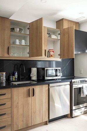 A modern kitchen with wooden cabinets, a stainless steel dishwasher, a microwave, and an oven.