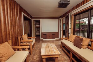 A room with wooden furniture, a bench, and a door leading to another room. - The Teak House (San Rafael)