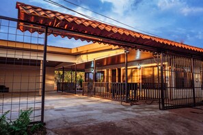 Um espaço ao ar livre coberto com cerca de metal, piso de concreto e um edifício com telhado de telhas.