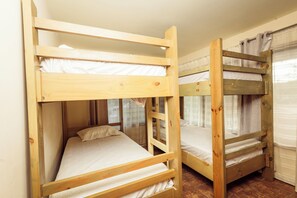 A room with two bunk beds, each with a wooden frame and white bedding. - The Teak House (San Rafael)