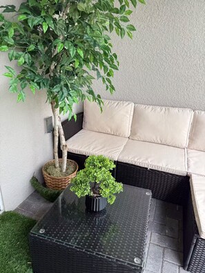 Eine Sitzecke mit einer gepolsterten Couch, einer Zimmerpflanze auf einem Tisch und einem kleinen Baum im Korb.