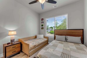 A bedroom with a bed, a bedside table with a lamp, a small wooden chair, and a window with blinds. - Skier's Cove - Lake Access & Deeded Boat Slip (Granite Shoals)