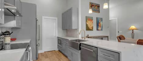 Una cocina moderna con gabinetes grises, una campana de acero inoxidable y un lavavajillas integrado.