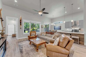 A spacious living room with a large sofa, a coffee table, and a fireplace. There is a kitchen area with modern appliances and a dining area with a table and chairs. - Skier's Cove - Lake Access & Deeded Boat Slip (Granite Shoals)