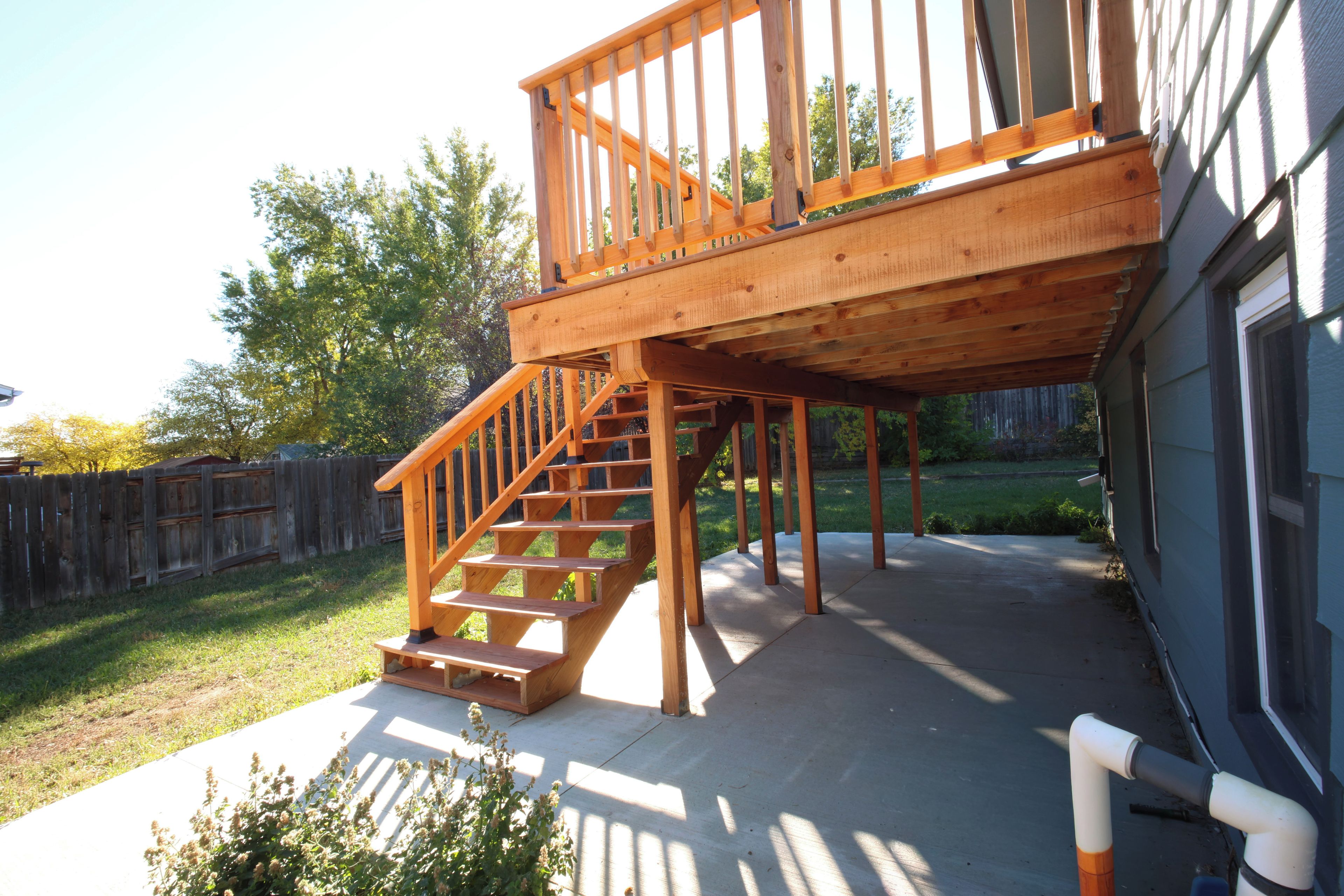 A wooden deck with a staircase leading to a second-story deck area.