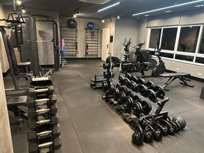 Ein Fitnessstudio mit Gewichtstrainern, Trainingsgeräten und einem großen Fenster.