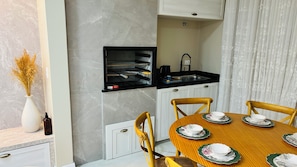 A modern kitchen with a built-in oven, a sink, and a dining area with a wooden table set for four. - Ravello Elegance Center Foz do Iguaçu (Foz do Iguaçu)