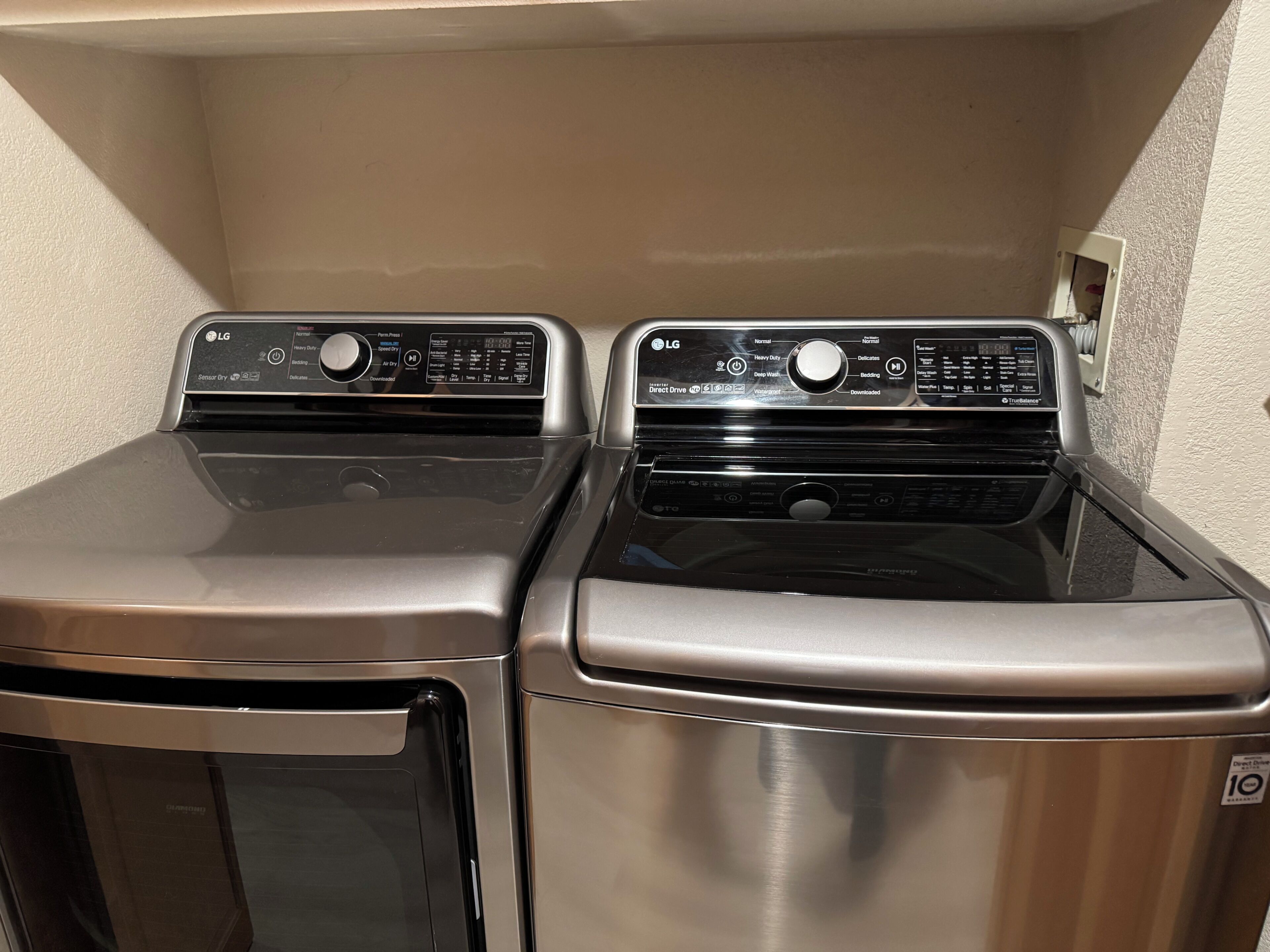 A laundry area with two front-loading washing machines and a dryer.