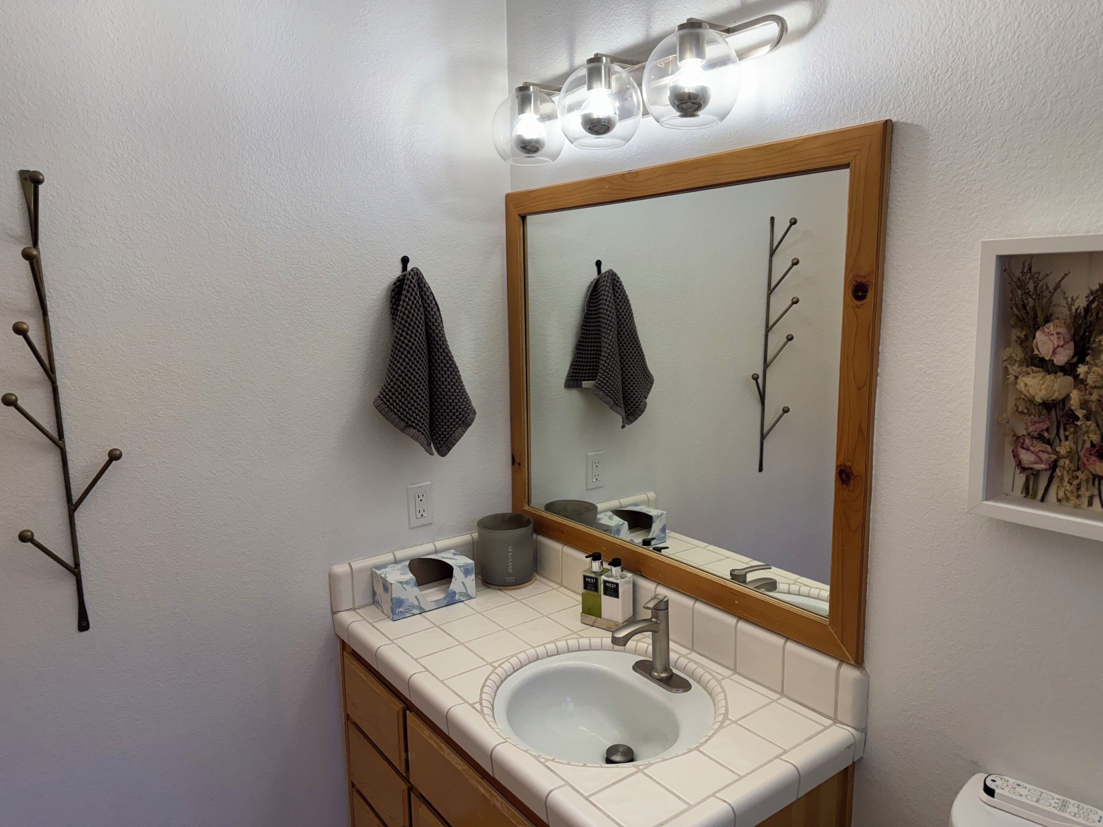 A bathroom with a white sink, a mirror with a wooden frame, and a towel rack with two towels.