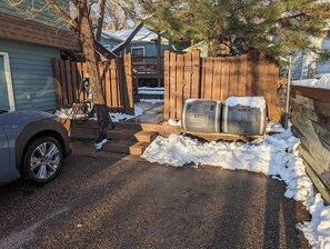 A residential driveway with a car parked on the left, a wooden fence, and a snow-covered area. - Golden Getaway w/ EV Charger - 14 min to Red Rocks! (Golden)