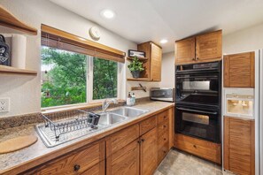 A kitchen with wooden cabinets, a built-in oven, a microwave, and a sink with a dish rack. - Golden Getaway w/ EV Charger - 14 min to Red Rocks! (Golden)