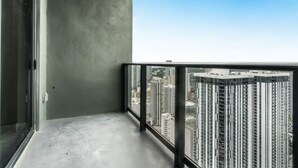 Ein Balkon mit Blick auf die Stadt, einem Betonboden und einer Glastür.