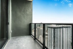 Ein Balkon mit Blick auf die Stadt, einem Betonboden und einer Glastür.