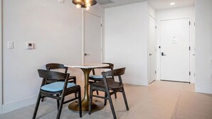 Ein Essbereich mit einem runden Tisch, vier Stühlen, einer Deckenleuchte und einer Tür im Hintergrund.