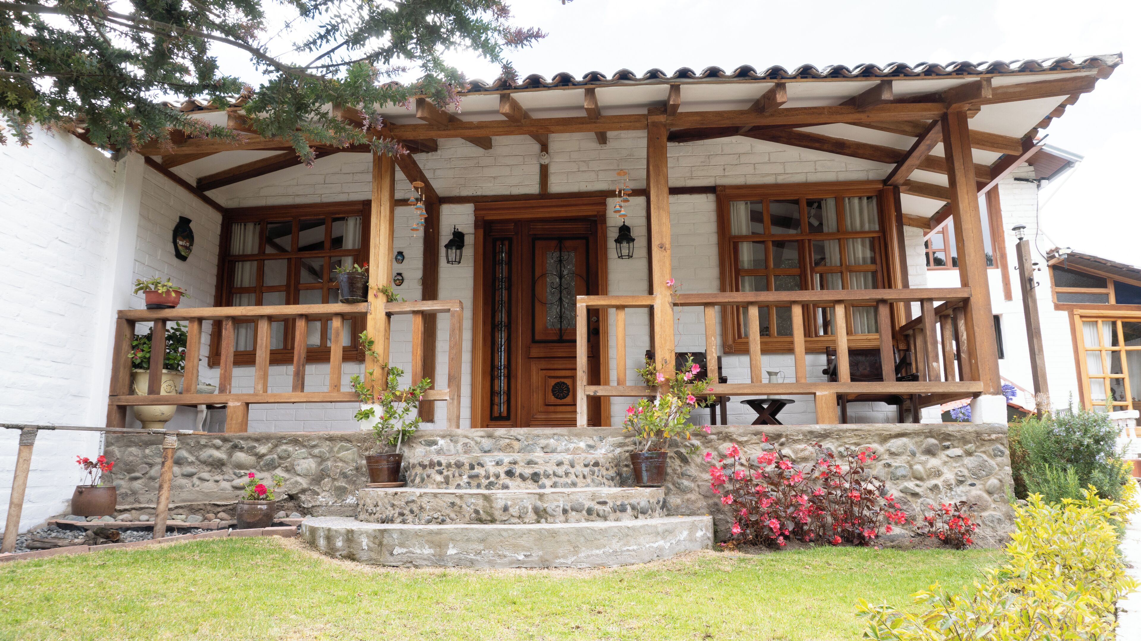 A traditional house with a stone facade, wooden porch, and a tiled roof.