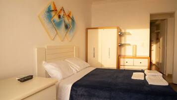 Quarto com cama, mesa de cabeceira, guarda-roupa e um quadro na parede.