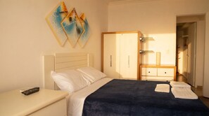 Quarto com cama, mesa de cabeceira, guarda-roupa e um quadro na parede.