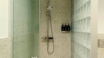 Ducha con puerta de vidrio, cabezal de ducha manual y grifo empotrado.