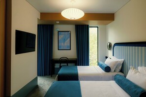 A hotel room with two beds, a desk, a chair, a large window, and a hanging light fixture. - Proza Hotel & Restaurant (Kutaisi)