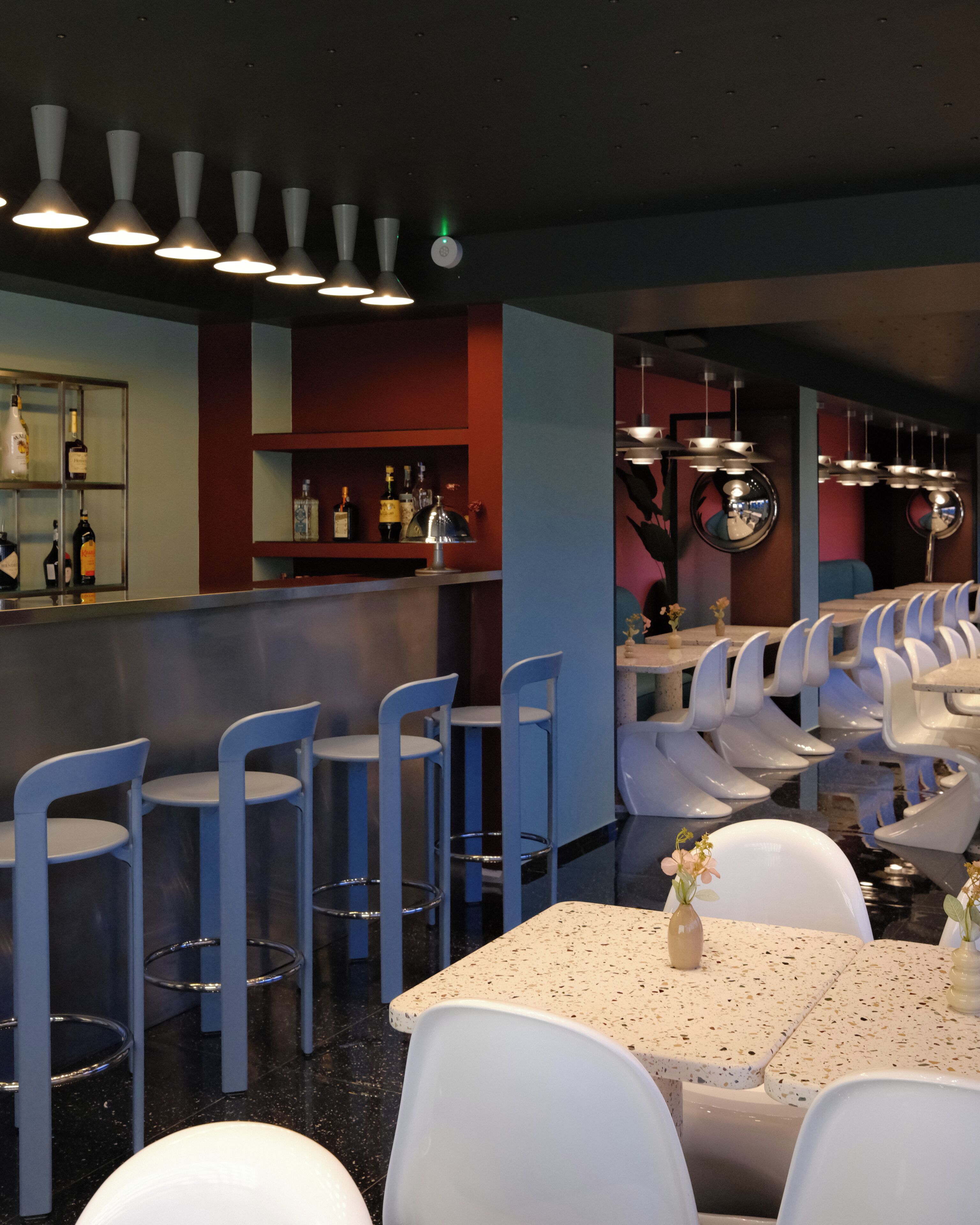 A restaurant interior with bar seating, high chairs, and a bar counter with bottles.