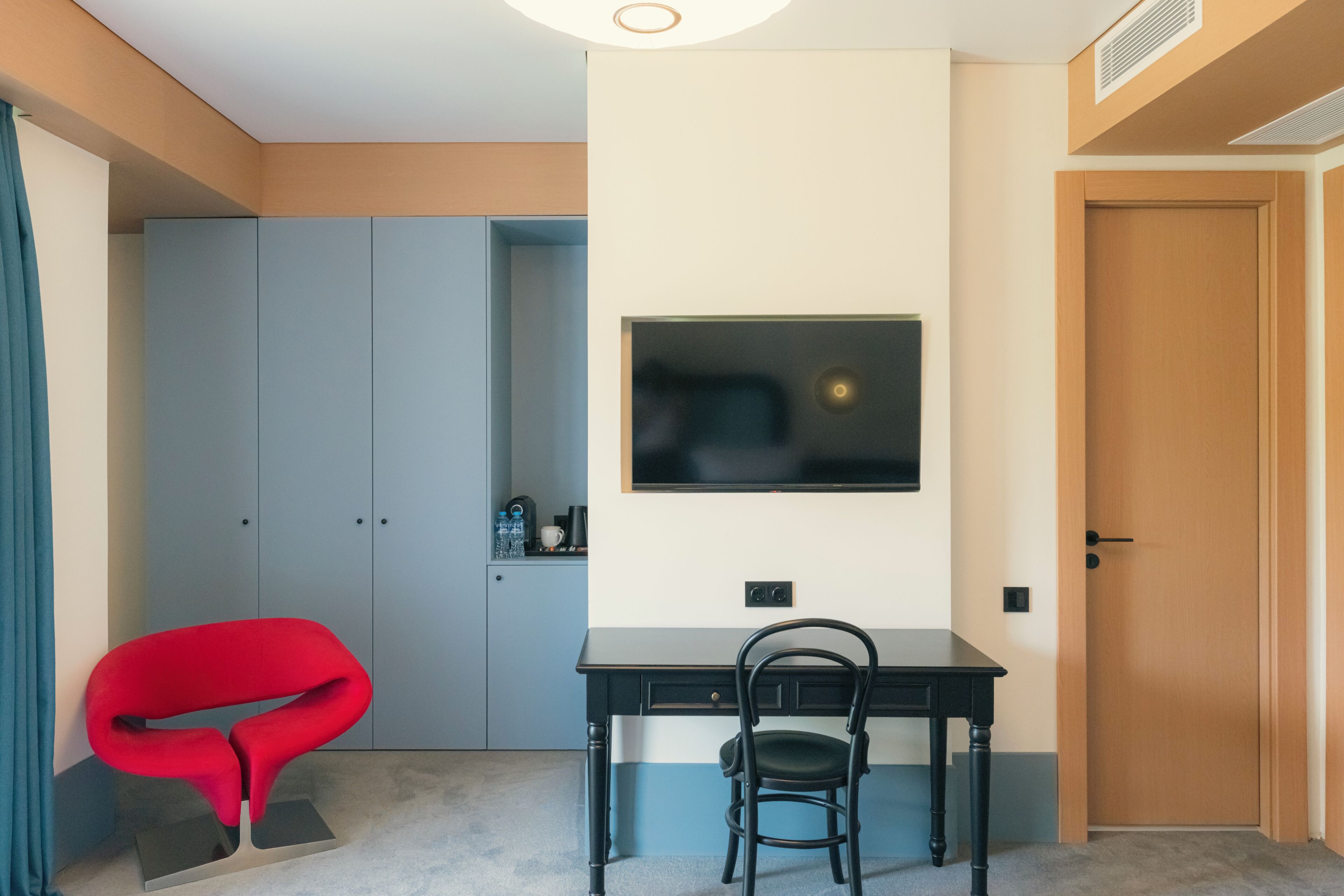 Una habitación moderna con escritorio, silla y televisor montado en la pared.