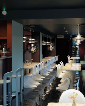 A modern restroom with multiple urinals and a reflective ceiling.
