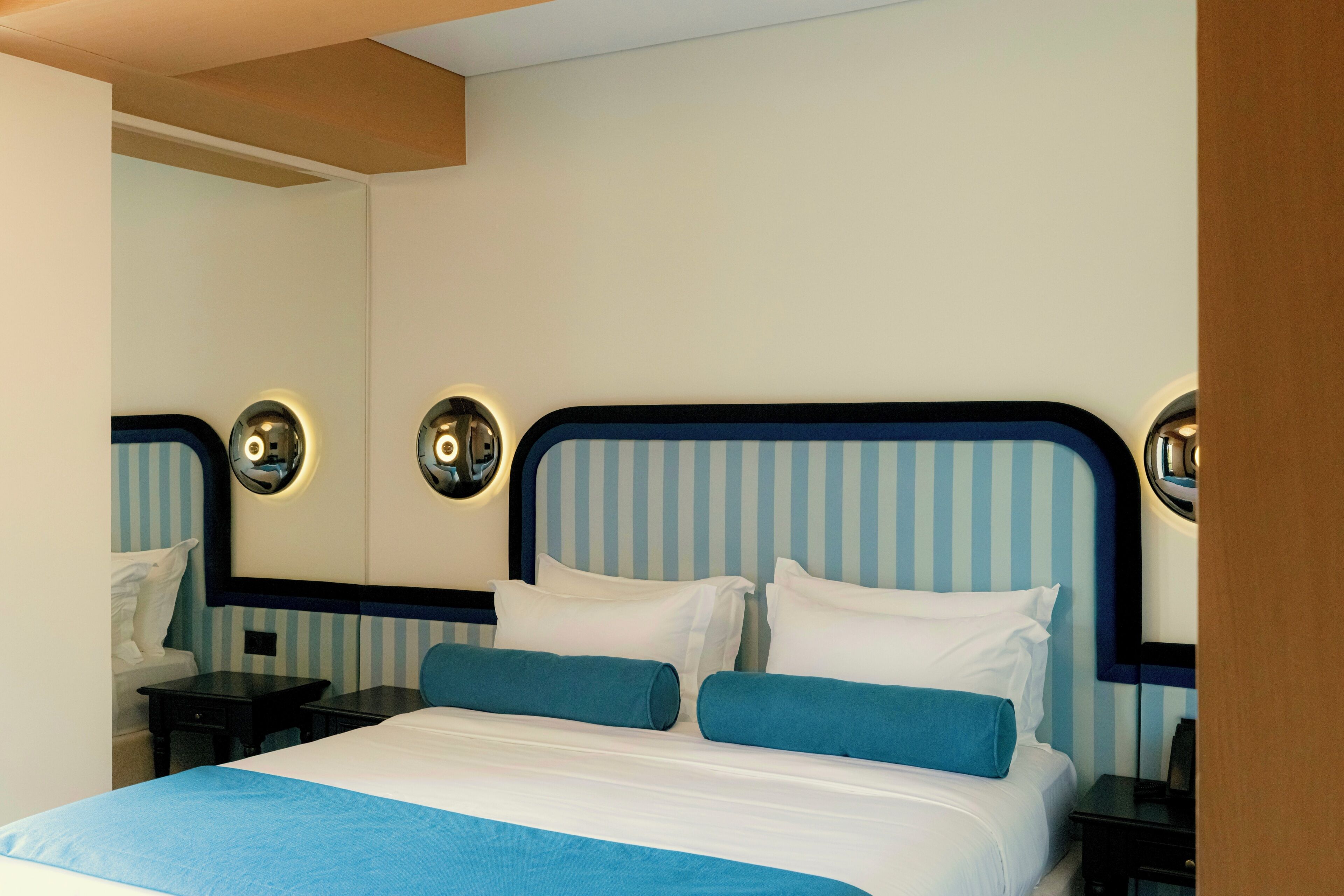 Ein Hotelzimmer mit einem Bett, zwei Nachttischen, einem Spiegel und Wandleuchten.