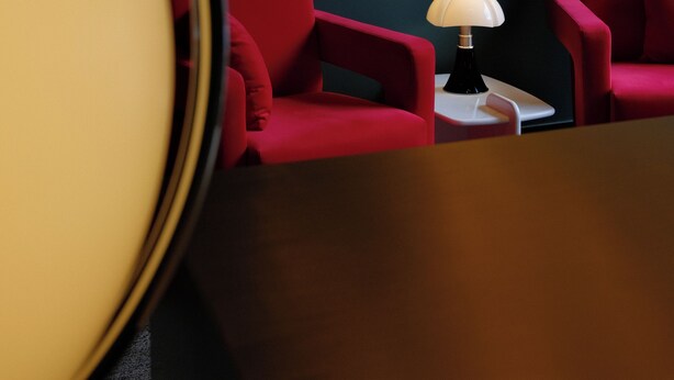 A room with two red chairs, a small white table, and a lamp.