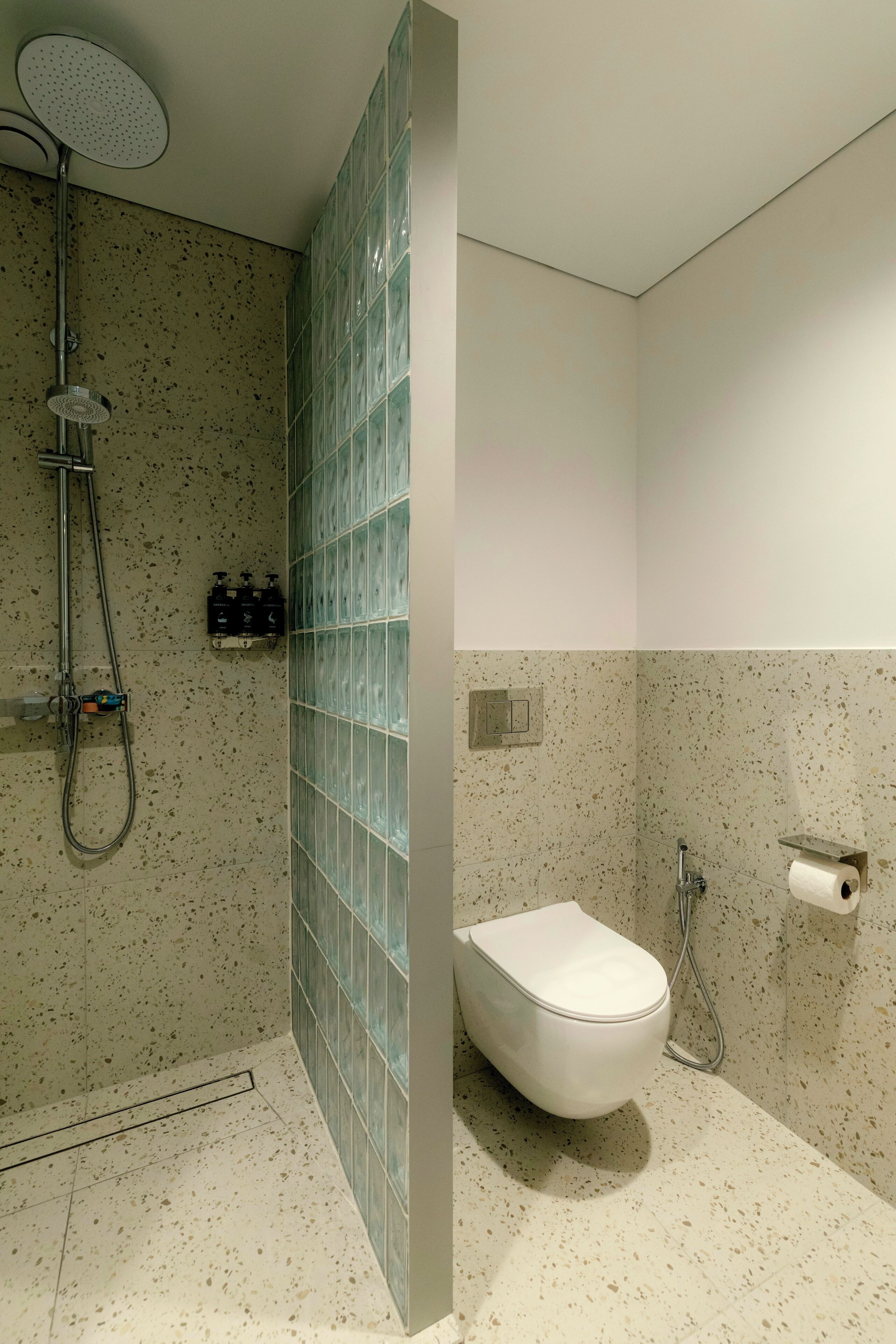 Un baño con ducha, inodoro y pared de azulejos.