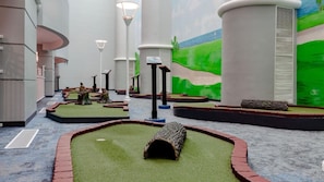 A model landscape with miniature trees, a log, and a small pond, surrounded by brick borders and white pillars.