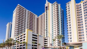A high-rise hotel with multiple floors, balconies, and a central courtyard with palm trees.