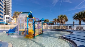 Een waterpark met een glijbaan, een zwembad en een strandgedeelte met ligbedden.